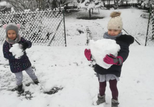 Dzieci w ogrodzie przedszkolnym lepią kule ze śniegu.